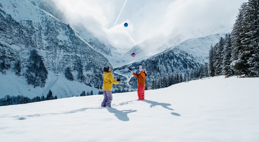 Children are playing in the deep snow with colorful balls.