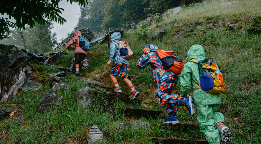 Kids in colorful rain gear explore the green nature