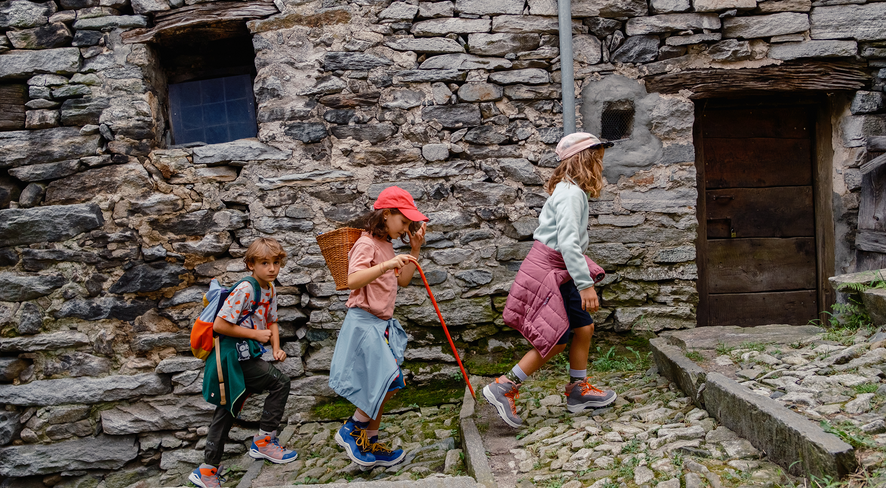 Three kids are hiking together through a stone village
