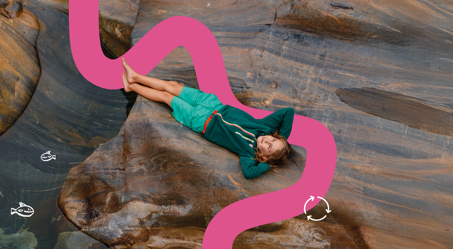 Kid relaxing on a rock by the water
