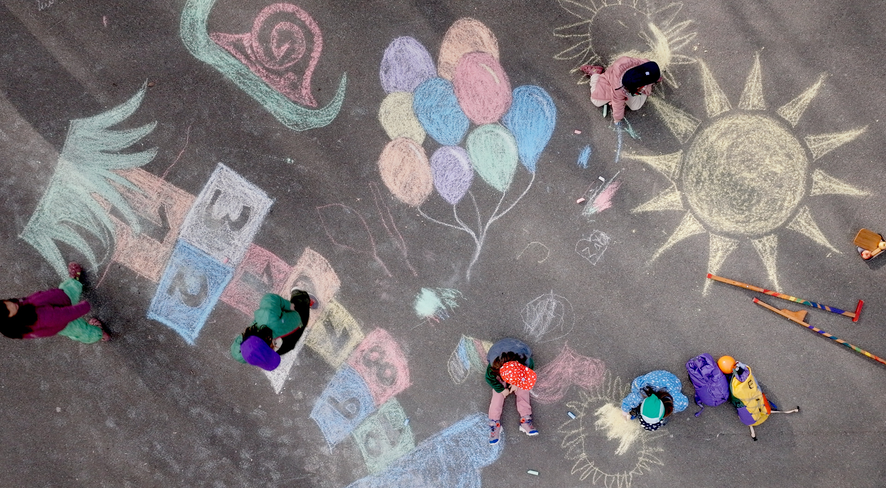 Kids playing on a playground painted with colorful chalk